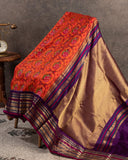 Orange twill Patola saree with a contrast purple border