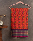Orange twill Patola saree with a contrast purple border