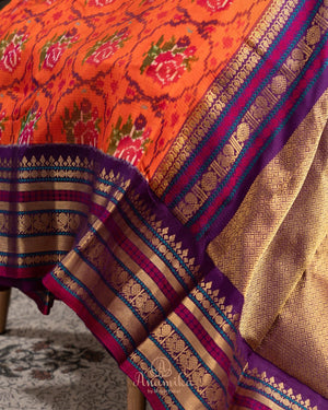 Orange twill Patola saree with a contrast purple border