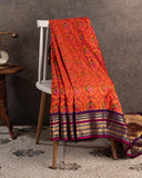 Orange twill Patola saree with a contrast purple border