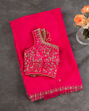 Organza saree in hot pink with a zardosi work border and a heavily embroidered sleeveless blouse