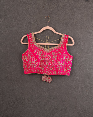 Organza saree in hot pink with a zardosi work border and a heavily embroidered sleeveless blouse