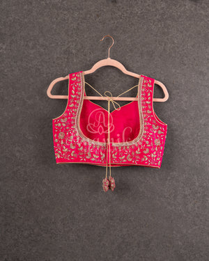 Organza saree in hot pink with a zardosi work border and a heavily embroidered sleeveless blouse