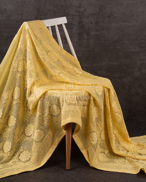 Chikankari georgette saree in yellow paired with a sleeveless off white blouse