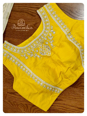 Off white organza saree with a sleeveless yellow blouse