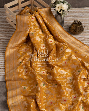 A grand Banarasi silk saree in yellow with floral jaal design and meenakari buttas