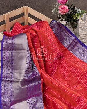 Reddish Pink Kanchipattu saree with a contrast purple blouse